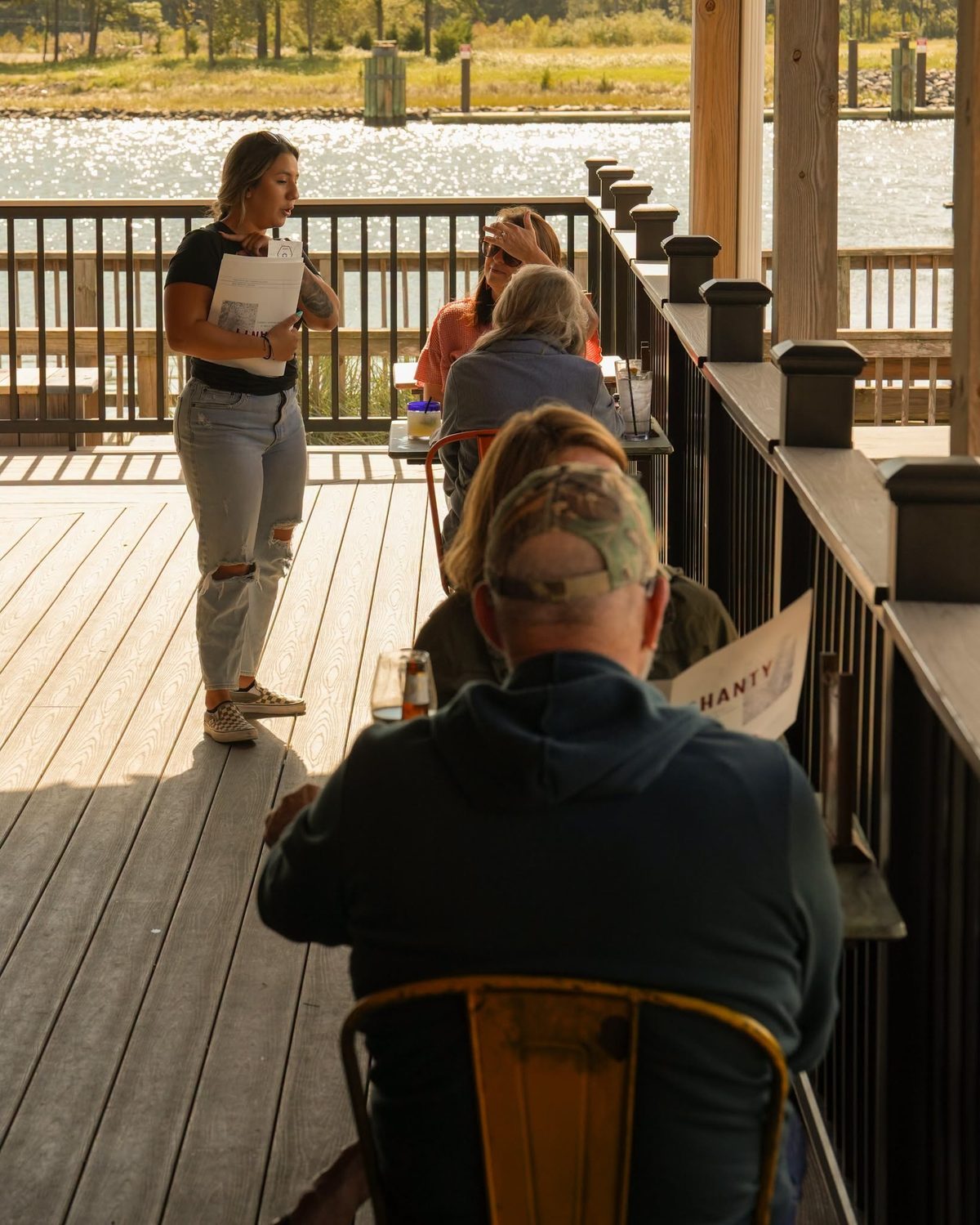 A server with guests on The Shanty deck
