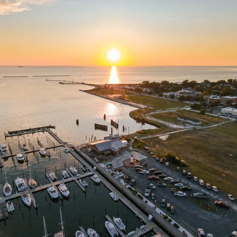 Aerial view of the Cape Charles harbor and marina at sunset, with The Shanty on the water and the town behind it