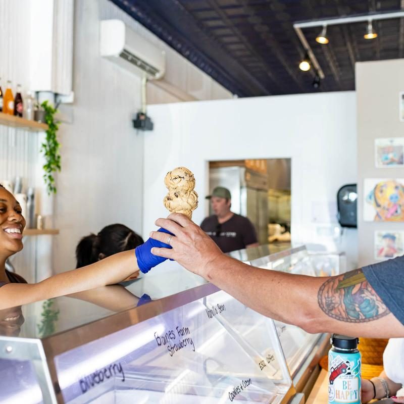 A Brown Dog scooper handing a cone across the counter